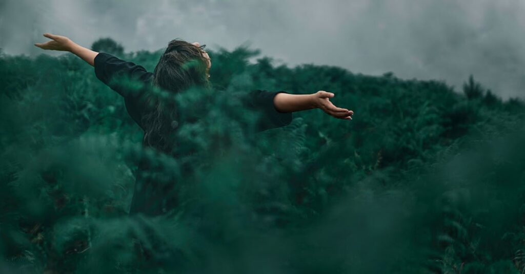 pexels-photo-1583582-1583582 A woman with open arms enjoying freedom in a foggy green landscape.