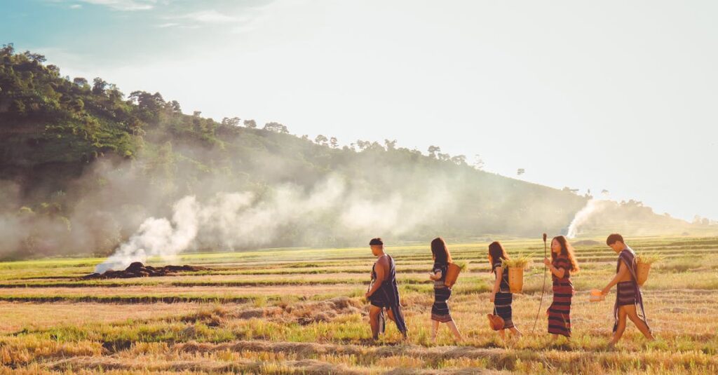 pexels-photo-1679925-1679925 Group of people in traditional wear walking across a scenic countryside field at dawn.