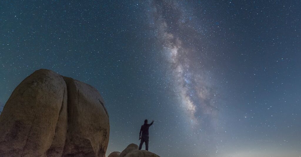 pexels-photo-5489489-5489489 A person silhouetted against the Milky Way starry night in a desert landscape.