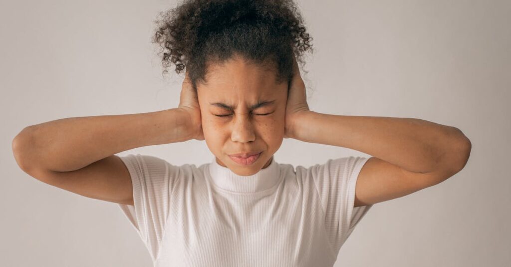 pexels-photo-7114756-7114756 Despaired African American teenage girl with black hair and closed eyes covering ears while standing on white background in light studio