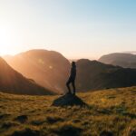 Silhouette of a person standing on a hill during sunrise in Cumbria, England with scenic mountain views. Perfectionism and creative flow